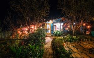 a house lit up at night with lights at Orchards House - The Hidden Tribe in Manāli