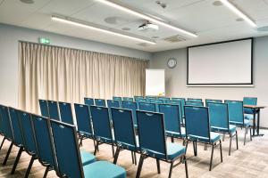 une salle de conférence avec des chaises bleues et un écran dans l'établissement Focus Hotel Poznań, à Poznań