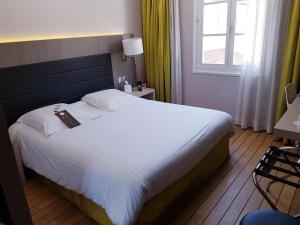 a bedroom with a large white bed with a window at Logis Hôtel Les Tuileries in Féy