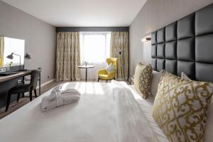 a hotel room with a large white bed with a desk at Gresham Belson Hotel Brussels in Brussels