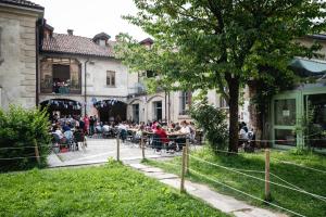 grupa ludzi siedzących przy stołach przed budynkiem w obiekcie Un posto a Milano - guesthouse all'interno di una cascina del 700 w Mediolanie