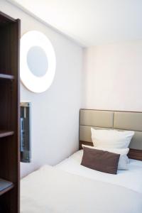 BASE II - Das Bed & Breakfast bei Basel (Lörrach) في لاروش: غرفة نوم بسرير ابيض ومخدة بنية اللون