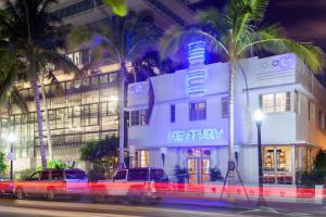 two cars parked in front of a hotel with palm trees at Century Hotel in Miami Beach