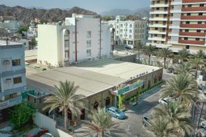 une vue sur une ville avec des palmiers et des bâtiments dans l'établissement Mutrah Hotel, à Mascate