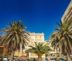 duas palmeiras em frente a um edifício amarelo em Magic View Apartments em Zadar