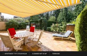 un patio con mesa y sillas bajo una sombrilla amarilla en HEJ Apartments Bayreuth, en Bayreuth