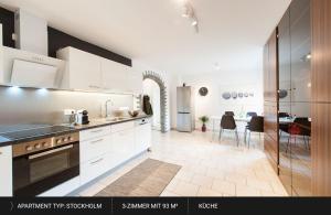 cocina con armarios blancos y comedor en HEJ Apartments Bayreuth, en Bayreuth