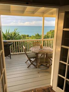 a table and chairs on a porch with the ocean at Breeze Cottage in Five Islands Village