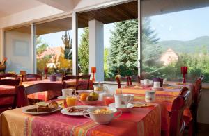 une salle à manger avec des tables et une grande fenêtre dans l'établissement Hôtel Restaurant Logis La Palette, à Wettolsheim