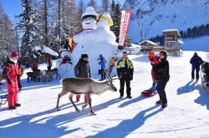 Eine Gruppe von Menschen und ein Schneemann und ein Reh im Schnee in der Unterkunft Ferienwohnungen am Lärchenweg in Sexten