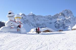 Eine Gruppe von Menschen, die neben einem Schneemann stehen in der Unterkunft Ferienwohnungen am Lärchenweg in Sexten