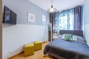 a bedroom with a bed and two yellow stools at ClickTheFlat Sienna Center Apart Rooms in Warsaw