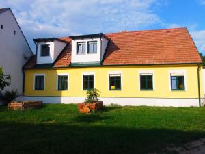 uma casa amarela e branca com um telhado vermelho em Gästehaus Weinviertel - Niederösterreich em Siebenhirten