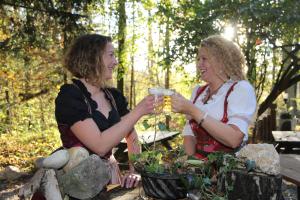 Duas mulheres sentadas numa mesa de piquenique com bebidas. em Gästehaus Weinviertel - Niederösterreich em Siebenhirten