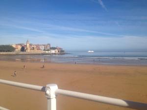 a view of a beach with people walking on the sand at Apartamentos Plaza Mayor in Gijón