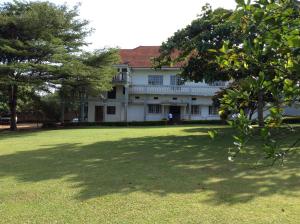 een groot wit huis met een boom in de tuin bij Skyway Hotel in Entebbe