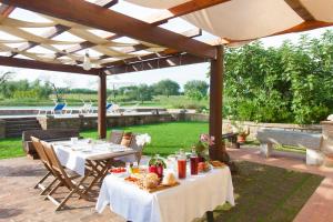 eine Terrasse mit Tischen und Stühlen unter einer Pergola in der Unterkunft FicOlivo in Pitigliano