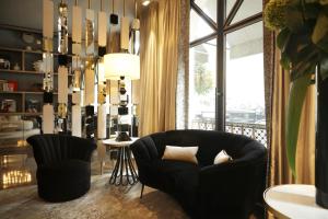 a living room with a black chair and a chandelier at Hôtel le Derby Alma by Inwood Hotels in Paris