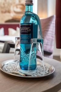 een fles water zittend op een bord met een glas bij Frommanns Landhotel in Buchholz in der Nordheide