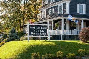 a house with a sign in front of a house at Telegraph House Motel in Baddeck