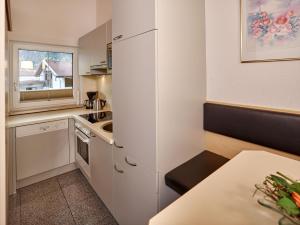 a small kitchen with white cabinets and a table at Gästehaus Renate in Längenfeld