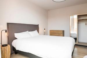 a white bedroom with a large bed and a window at Skyline Flats Gent in Ghent