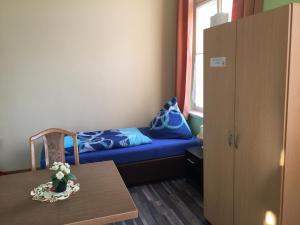 Cette petite chambre comprend un lit bleu et une table. dans l'établissement Zimmerfrei-Dresden mit Bad-Miniküche Self Check In 24-7, à Dresde