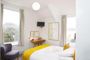 a bedroom with a bed and a chair and windows at The Lerryn in Falmouth