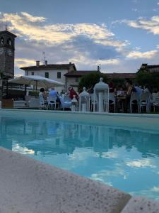 uma piscina com uma torre de relógio ao fundo em La Locanda Del Grop em Tavagnacco