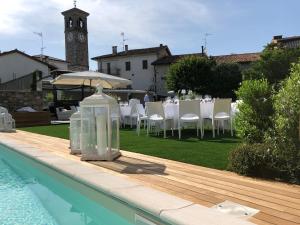 uma piscina com mesa e cadeiras e uma torre do relógio em La Locanda Del Grop em Tavagnacco