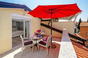 a patio with a table and chairs and a red umbrella at Apartments Babo in Rovinj