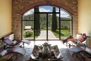 une chambre avec une grande fenêtre et une femme assise dans des chaises dans l'établissement Castello di Spaltenna Exclusive Resort & Spa, à Gaiole in Chianti