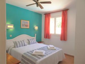 - une chambre avec un lit blanc et un mur bleu dans l'établissement Apartamentos Alta Galdana, à Cala Galdana