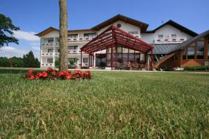 ein großes Gebäude mit roten Blumen im Gras in der Unterkunft Hotel Pension Fent in Bad Füssing