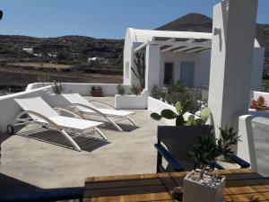 een patio met witte stoelen en een tafel bij Sun Anemos Resort in Oia