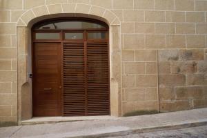 uma porta de madeira num edifício de tijolos com um arco em Apartamento Turístico Centro Monumental -- Caceres em Cáceres