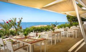 eine Terrasse mit Tischen und Stühlen und Meerblick in der Unterkunft Sunflower Camping in Novigrad Istria