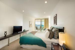 a bedroom with a bed with a television and a balcony at at Marina Shores in Airlie Beach