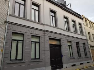 un edificio blanco con puertas y ventanas negras en Homey - Kortrijk, en Cortrique