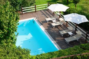 een zwembad met 2 stoelen en een parasol bij Agriturismo La Vecchia Quercia in San Cipriano Picentino