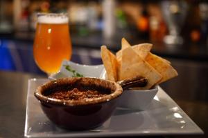 um prato com uma tigela de salsa, batatas fritas e uma cerveja. em Auberge de Jeunesse Le Camp De Base em LʼAnse-Saint-Jean