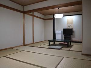 ein Wohnzimmer mit einem Tisch und einem TV in der Unterkunft Kimatsu Ryokan in Hiroshima