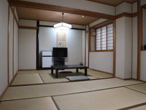 Zimmer mit einem TV und einem Tisch. in der Unterkunft Kimatsu Ryokan in Hiroshima