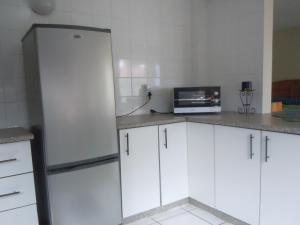 a kitchen with white cabinets and a refrigerator at Liz' Cottage in Mbabane