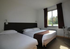 A bed or beds in a room at Logis Hôtel Lodge La Valette