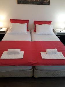 two beds in a bedroom with red and white sheets at Private Home Rifat in Dubrave Gornje