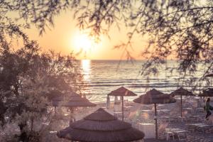 uma praia com guarda-sóis e o oceano ao pôr do sol em Grand Hotel Costa Brada em Gallipoli