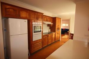 a kitchen with a white refrigerator and wooden cabinets at Verona Vineyard Cottage in Pokolbin