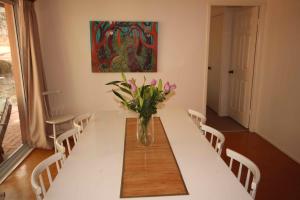 a dining room table with a vase of flowers on it at Verona Vineyard Cottage in Pokolbin