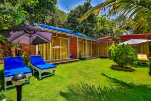 una casa con un cortile con sedie e ombrellone di Zulu Land cottages - near Curlies beach shack and shiva valley - Anjuna beach ad Anjuna